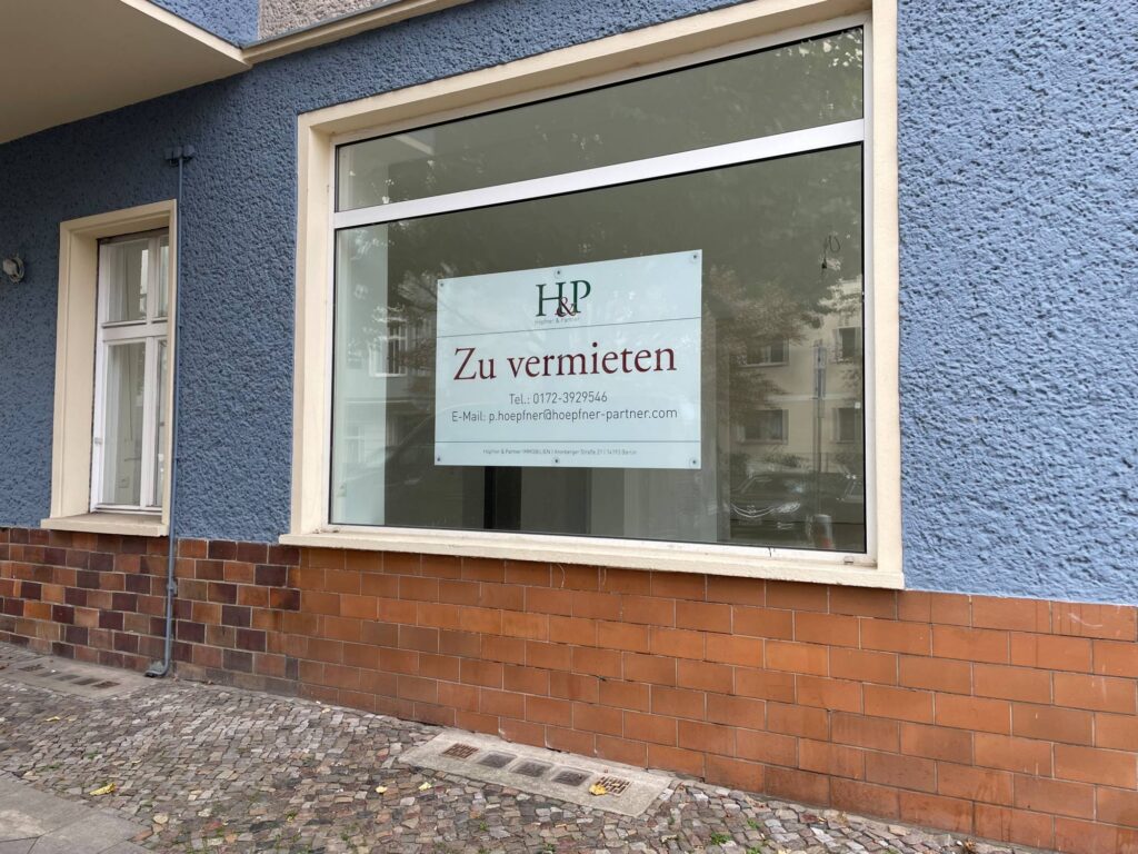 Hinweisschild »Zu vermieten« von Höpfner & Partner Immobilien im Schaufenster eines Ladenlokals